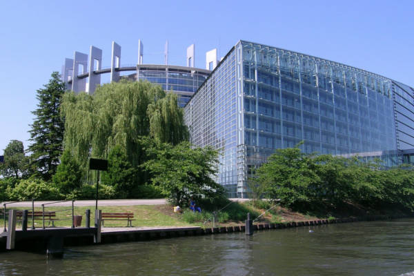 Modernes Glasgebäude am Flussufer mit Bäumen