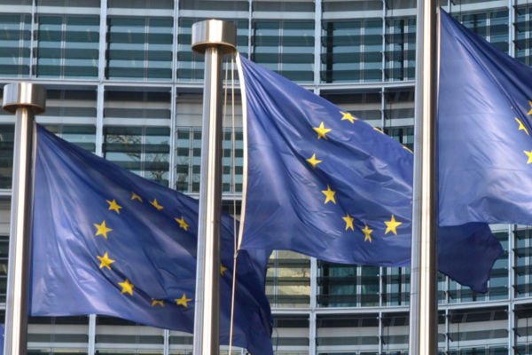 EU-Flaggen vor modernem Glasgebäude
