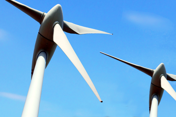 Zwei Windkraftanlagen vor blauem Himmel