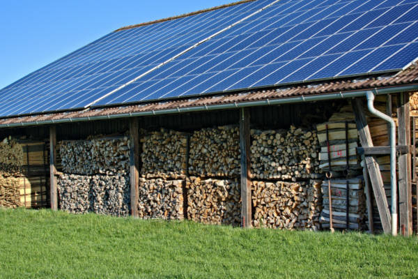 Solarpaneele auf Dach über gestapeltem Brennholz