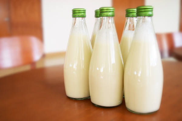 Vier Glasflaschen mit Milch auf Holztisch