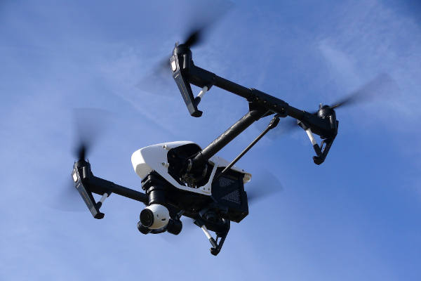 Fliegende Kameradrohne vor blauem Himmel